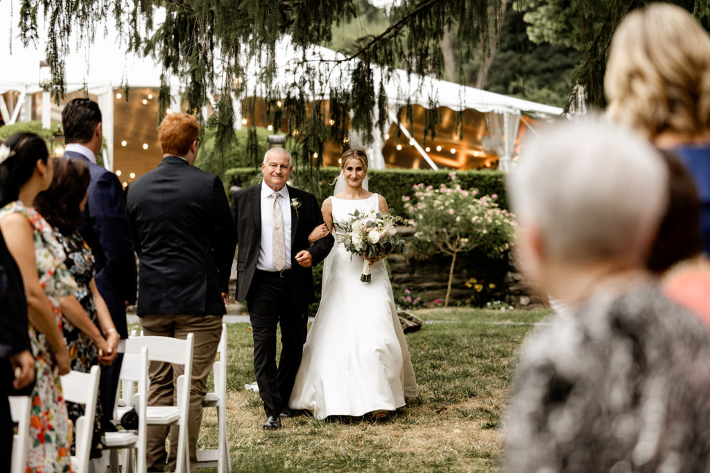 bride being walked by father down the aisle for wedding ceremony