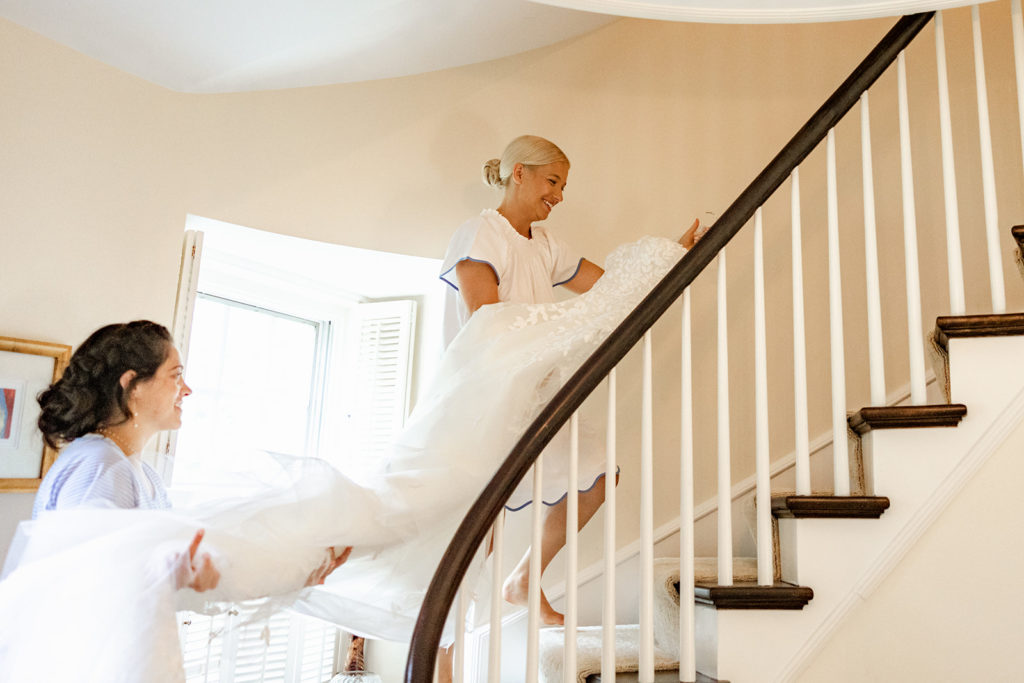 Bride carrying wedding dress up stairs
